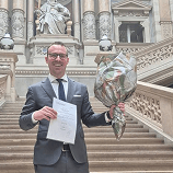 RAP-Absolvent mit Urkunde und Blumen im Justizpalast
